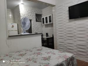 um quarto com uma cama e uma televisão de ecrã plano em Recanto em Mongaguá