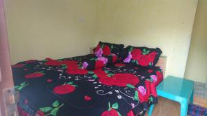 ein Schlafzimmer mit einem Bett mit roten Blumen darauf in der Unterkunft Penginapan Biringta in Berastagi