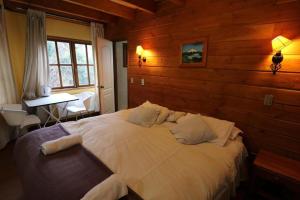a bedroom with a white bed in a wooden wall at Hostal Santa Maria Huife in Pucón