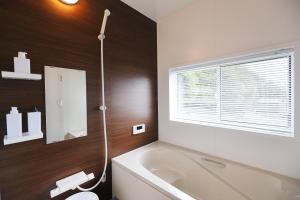 a bathroom with a tub and a toilet and a window at Villas Asama no Iori in Fujiyoshida