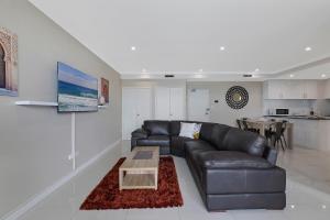 a living room with a leather couch and a table at Lakeside Waterfront Apartment The Entrance in The Entrance