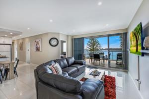 a living room with a leather couch and a table at Lakeside Waterfront Apartment The Entrance in The Entrance