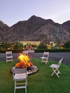 a fire pit in a yard with chairs and mountains at Hidden Valley Farm Home AE in Bulaydah