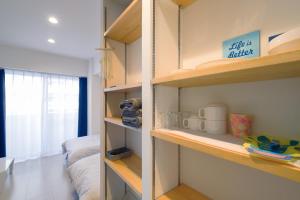 那覇市にあるグッドライフアパートメント那覇の木製の棚、ベッド、窓が備わる客室です。