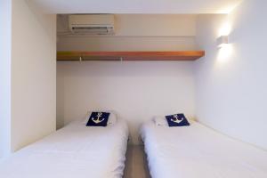 那覇市にあるグッドライフアパートメント那覇の白い壁の小さな部屋のベッド2台
