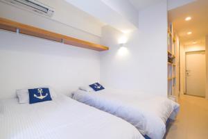 那覇市にあるグッドライフアパートメント那覇の白い壁の客室内のベッド2台