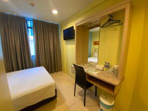 Habitación de hotel con cama y escritorio con espejo. en SRP Hotel Sdn Bhd en Batu Caves