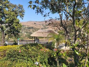 a small hut with a thatched roof in a garden at Thula Du Estate - one bed apartment in Mbabane