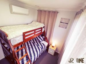 a small bedroom with a bunk bed and a small lamp at JZ One in Box Hill