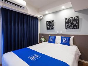 a bedroom with a bed with blue and white pillows at Living Inn Asahibashiekimae Premier in Naha