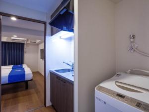 a bathroom with a sink and a bed and a mirror at Living Inn Asahibashiekimae Premier in Naha