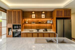 a kitchen with wooden cabinets and a stainless steel refrigerator at Villa Uma Berawa by Nakula in Canggu