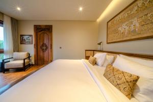 duże białe łóżko w pokoju z krzesłem w obiekcie Villa Uma Berawa by Nakula w mieście Canggu