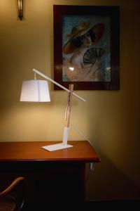 un escritorio con una lámpara y una pintura en la pared en Hotel San Genesio en Fabbrico