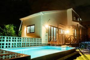a swimming pool in front of a house at night at Hanare AOZORA in Onna