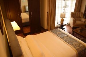 a bedroom with a bed and a chair and a window at Shinepukur Suites in Dhaka
