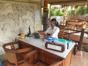 a woman sitting at a table using a computer at Tirta Ayu Hotel and Restaurant in Tirtagangga