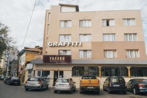 um edifício com carros estacionados em frente em Graffiti Hotel em Bucareste