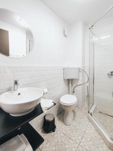 uma casa de banho branca com um lavatório e um WC em Graffiti Hotel em Bucareste