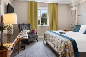 a bedroom with a bed, desk, chair and a lamp at Cork's Vienna Woods Hotel & Villas in Cork