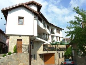 a white building with a balcony and a car at Family Hotel Silvestar in Veliko Tŭrnovo