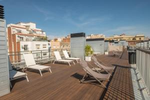eine Terrasse mit Liegestühlen auf einem Gebäude in der Unterkunft Aparthotel Bcn Montjuic in Barcelona