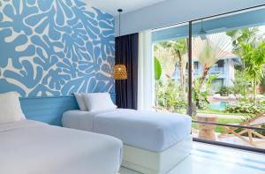 two beds in a room with a view of a patio at The Peri Hotel Hua Hin - SHA PLUS in Hua Hin