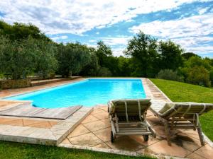 una piscina con 2 tumbonas junto a ella en Belvilla by OYO Villa Sara, en Lucignano