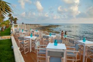 a restaurant on the beach with tables and chairs at Aquamare Beach Hotel & Spa in Paphos
