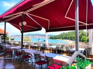 a patio with tables and chairs and a red umbrella at Premium Mobile Home ZEN SPOT 280 in Jezera