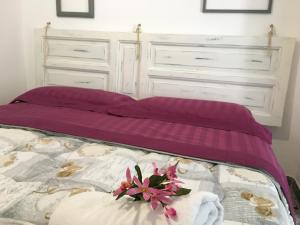 een bed met paarse lakens en een bloem erop bij Casa Bettina in Ostuni