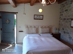 a bedroom with a white bed with a stone wall at B&B A Casa Di Piero in San Massimo