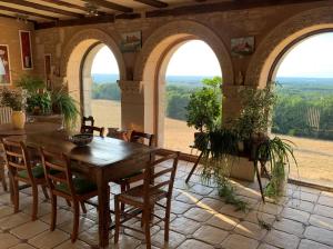 uma sala de jantar com mesa, cadeiras e janelas em Nature et Piscine au sommet du Périgord em Tourtoirac