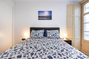 Schlafzimmer mit einem Bett mit einer blauen und weißen Bettdecke in der Unterkunft Apartamento Soho Málaga in Málaga