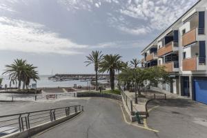 a building next to a beach with palm trees at Merlín 1-1 in Playa de San Juan