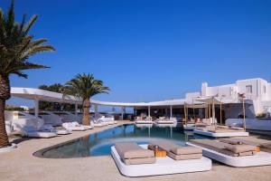 a beach area with a pool, chairs, and tables at Andronikos Hotel in Mikonos