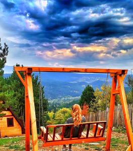 una mujer sentada en un columpio mirando la vista en Fikri Atalay Konağı Bungalov Evleri, en Mengen