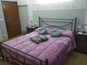 una camera da letto con letto rosa e cuscini sopra di Appartamento Grey ad Arezzo