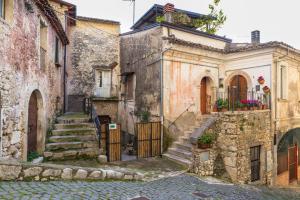 ein altes Steinhaus mit Treppe in einer Straße in der Unterkunft Casa Vacanze Porta Manfredi in Arce