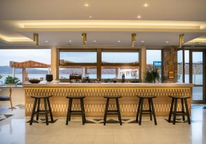 a bar in a restaurant with four bar stools at Elounda Akti Olous (Adults Only) in Elounda