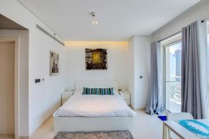 a white bedroom with a bed and a large window at Stylish Studio in West Avenue Dubai Marina in Dubai