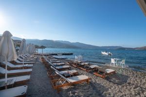 una fila de sillas y sombrillas en una playa en Elounda Akti Olous (Adults Only), en Elounda