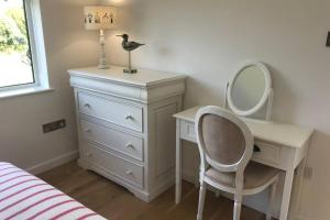 a bedroom with a desk with a mirror and a dresser at Barton on Sea self contained, stunning sea views in Barton on Sea