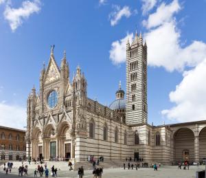 duży budynek z wieżą zegarową przed nim w obiekcie Suite al Duomo w Sienie