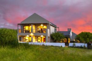 a house sitting on top of a hill with a sunset at Le Mahi Guest House in Langebaan