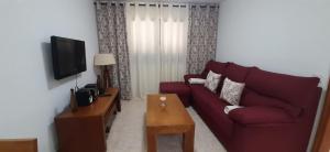ein Wohnzimmer mit einem roten Sofa und einem TV in der Unterkunft Casa Corvina in Playa Blanca
