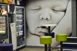 a large picture of a child on a wall with stools at ibis budget Pau Lescar in Lescar