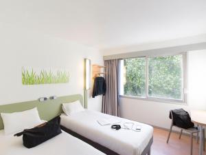 um quarto de hotel com duas camas e uma janela em ibis budget Pau Lescar em Lescar