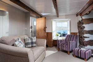 a living room with a couch and two chairs at Trevarrow Cottage in Coverack