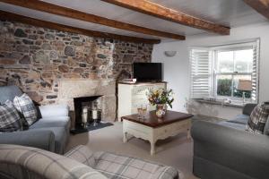 a living room with two couches and a stone wall at Trevarrow Cottage in Coverack